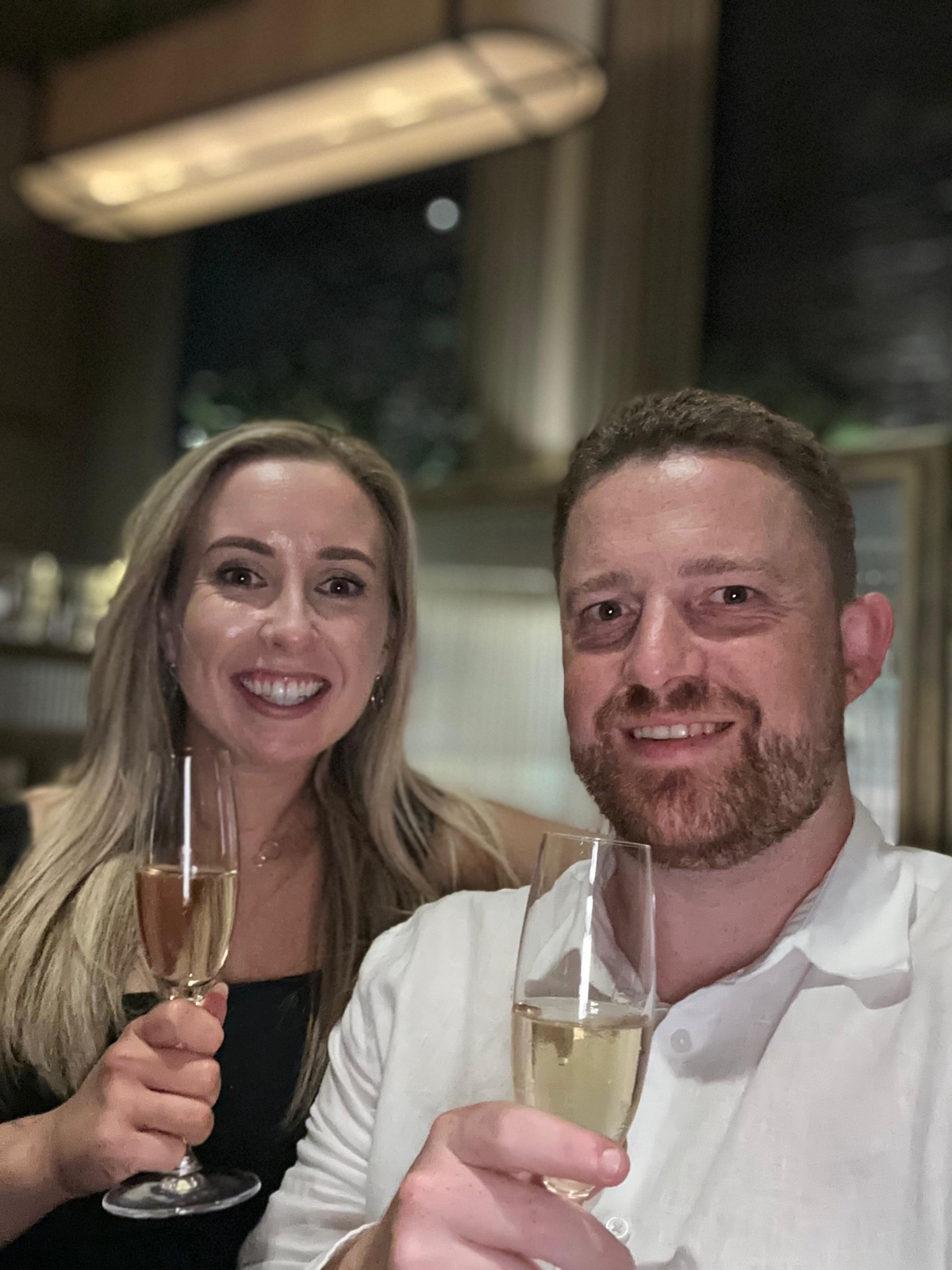 Zara and Alec raising glasses of champagne